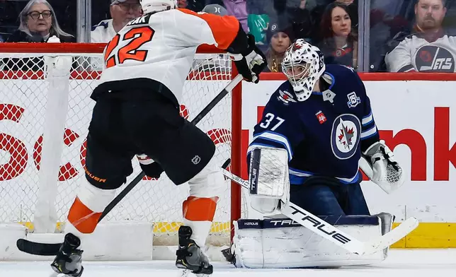 Winnipeg Jets goaltender Connor Hellebuyck (37) is scored on as Philadelphia Flyers' Christian Dvorak (22) looks on during second period NHL action in Winnipeg, Saturday, April 11, 2026. (John Woods/The Canadian Press via AP)