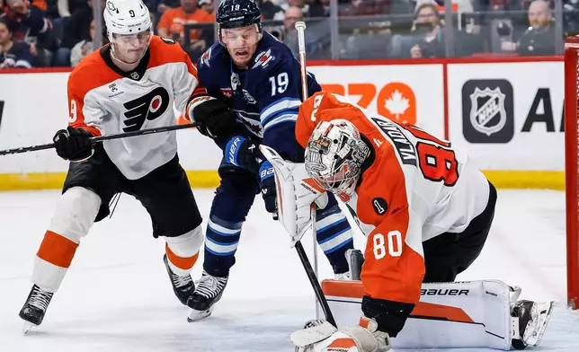 Winnipeg Jets' Jonathan Toews (19) digs for the rebound as Philadelphia Flyers goaltender Dan Vladar (80) saves the shot and Jamie Drysdale (9) defends during second period NHL action in Winnipeg, Saturday, April 11, 2026. (John Woods/The Canadian Press via AP)