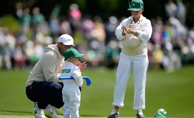 Scottie Scheffler, left, speaks with his son, Bennett, center, as his wife Meredith holds their son Remy, on the third hole during par-3 contest ahead of the Masters golf tournament at the Augusta National Golf Club, Wednesday, April 8, 2026, in Augusta, Ga. (AP Photo/Ashley Landis)