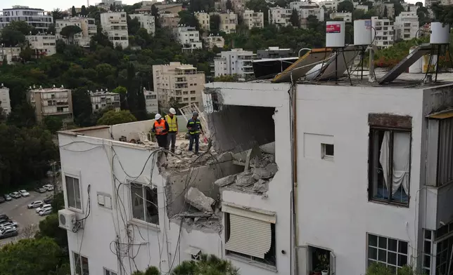 Israeli authorities inspect a damaged house following an Iranian missile strike in Haifa, Israel, Monday, March 30, 2026. (AP Photo/Ariel Schalit)