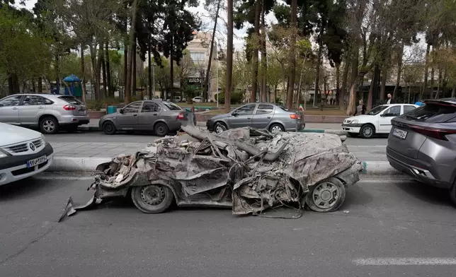 A damaged car is slotted between other vehicles after it was relocated from the area of a residential building that was hit in a U.S.-Israeli strike in Tehran, Friday, March 27, 2026. (AP Photo/Vahid Salemi)
