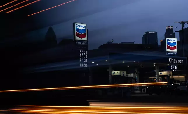 In this photo made with a slow shutter speed, a truck passes by gas prices that are displayed at a Chevron gas station, in downtown Los Angeles, Tuesday, March 31, 2026. (AP Photo/Jae C. Hong)