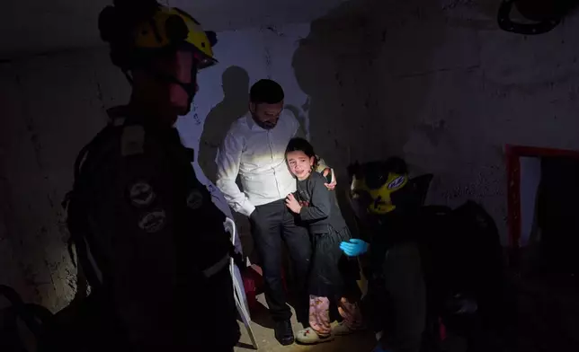 A young girl is comforted by her father and Israeli soldiers as they take cover in a bomb shelter during air raid sirens warning of incoming Iranian missile strikes in Bnei Brak, Israel, Wednesday, April 1, 2026. (AP Photo/Oded Balilty)