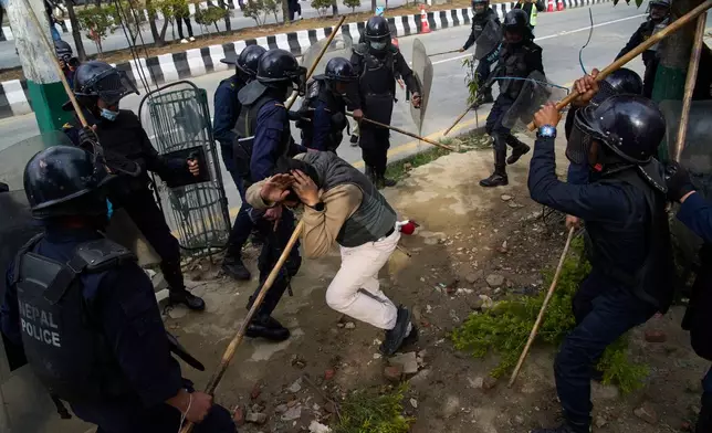Police officers use batons on a supporter of former Prime Minister Khadga Prasad Oli during a protest following his arrest over deaths linked to last year September protests, in Kathmandu, Nepal, Saturday, March 28, 2026. (AP Photo/Niranjan Shrestha)