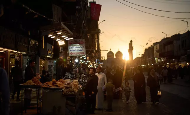 People visit a market near the Kadhimiya Shrine at sunset in the Shiite neighborhood of Baghdad, Iraq, Tuesday, March 31, 2026. (AP Photo/Leo Correa)
