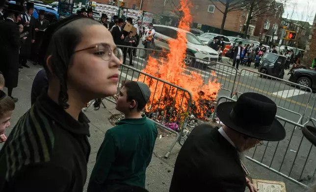 People stand near a fire during "biur chametz," a Jewish ritual where leavened food items are burned on the morning ahead of Passover, Wednesday, April 1, 2026, in New York. (AP Photo/Ryan Murphy)