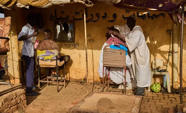 Street barbers work at a market in Omdurman, on the outskirts of Khartoum, Sudan, Sunday, April 26, 2026. (AP Photo/Bernat Armangue)