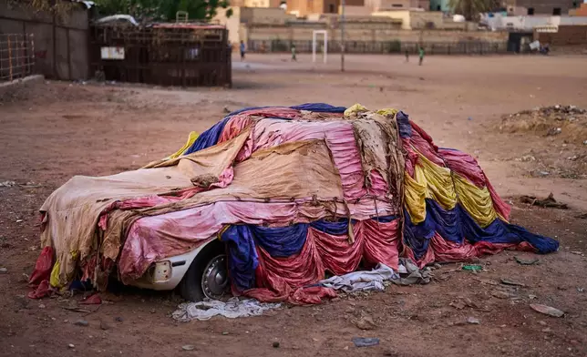 A car covered with cloths to protect it from the elements sits in a public park in Omdurman, on the outskirts of Khartoum, Sudan, Thursday, April 23, 2026. (AP Photo/Bernat Armangue)