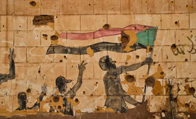 A painting depicting people holding the Sudanese flag is seen on a wall damaged by bullets and shrapnel in Omdurman, on the outskirts of Khartoum, Sudan, Thursday, April 23, 2026. (AP Photo/Bernat Armangue)