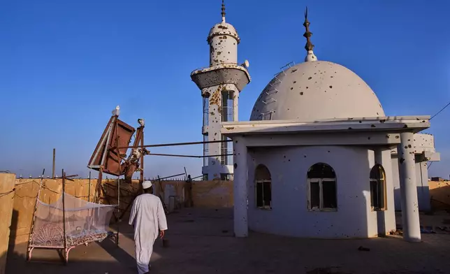 A man walks on the rooftop of the Sheikh GaribAllah Mosque damaged during the war in Omdurman, Sudan, on the outskirts of Khartoum, Friday, April 17, 2026. (AP Photo/Bernat Armangue)