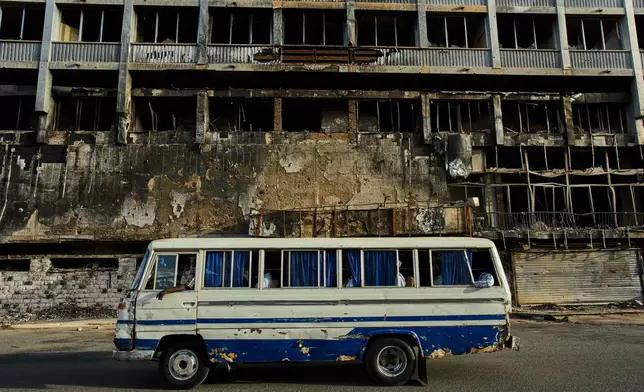 A bus drives past a hotel destroyed during the war in downtown Khartoum, Sudan, Sunday, April 19, 2026. (AP Photo/Bernat Armangue)