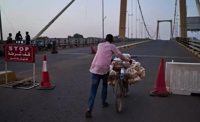 A man pushes his bicycle through a checkpoint in Khartoum, Sudan, Tuesday, April 21, 2026. (AP Photo/Bernat Armangue)