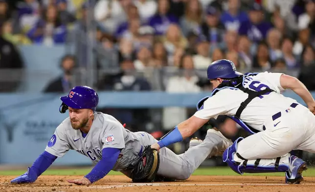 Chicago Cubs' Michael Busch, left, is tagged out by Los Angeles Dodgers catcher Will Smith, right, while attempting to score off a single hit by Alex Bregman during the fourth inning of a baseball game Friday, April 24, 2026, in Los Angeles. (AP Photo/Ryan Sun)