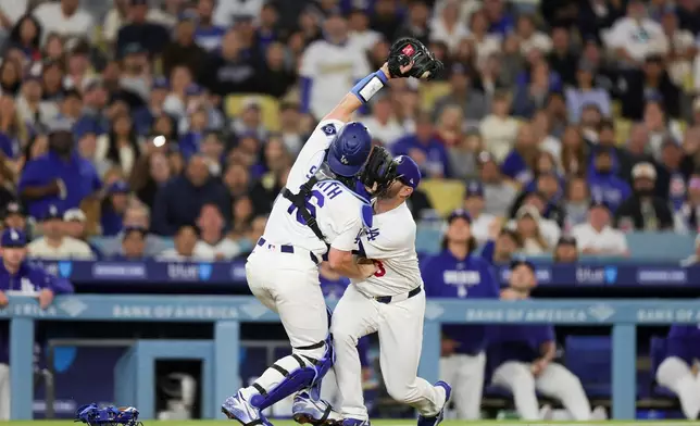 Los Angeles Dodgers catcher Will Smith, left, collides with third baseman Max Muncy, right, while catching a popout by Chicago Cubs' Ian Happ during the fourth inning of a baseball game Friday, April 24, 2026, in Los Angeles. (AP Photo/Ryan Sun)