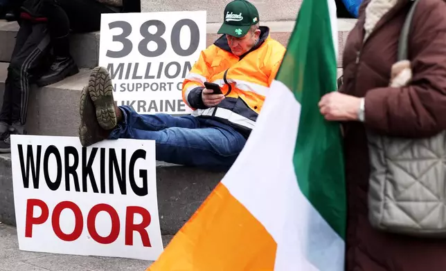 A protester sits on O'Connell Street in the heart of Dublin City center during the fifth day of a National Fuel Protest which has taken hold across Ireland, Saturday, April 11, 2026. (AP Photo/Peter Morrison)
