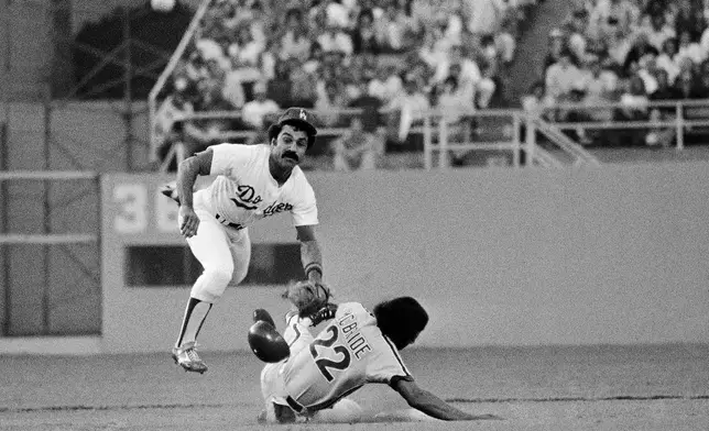 FILE - Los Angeles Dodgers second baseman Davey Lopes goes flying after forcing out Philadelphias Phillies Bake McBride in the front end of a double play hit into by Philadelphia's larry Bowa in the first inning of a baseball game, Oct. 4, 1977, in Los Angeles.. (AP Photo/File)