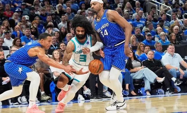 Charlotte Hornets guard Coby White (3) loses control of the ball as he tries to drive between Orlando Magic guard Desmond Bane, left, and center Wendell Carter Jr. (34) during the second half of an NBA play-in tournament basketball game, Friday, April 17, 2026, in Orlando, Fla. (AP Photo/John Raoux)