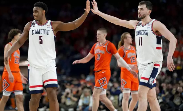 UConn forward Tarris Reed Jr. (5) high fives forward Alex Karaban (11) during the second half of an NCAA college basketball tournament semifinal game against Illinois at the Final Four, Saturday, April 4, 2026, in Indianapolis. (AP Photo/Abbie Parr)