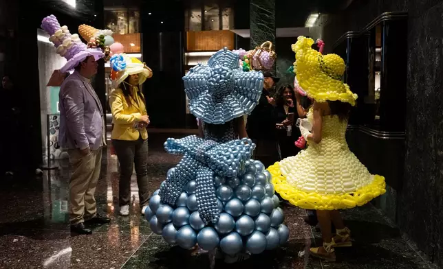 People wearing balloon costumes stand inside a building at Rockefeller Center during heavy rainfall at the Easter Bonnet Parade on Fifth Avenue, Sunday, April 5, 2026 in New York. (AP Photo/Adam Gray)