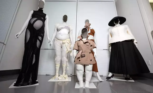 A Di Petsa dress by designer Dimitra Petsa appears on a pregnant mannequin, from left, an ensemble by Michaela Stark on a mannequin in Stark's image, a Burberry ensemble by Christopher Bailey on a mannequin image of Sinéad Burke, foreground, an ensemble by designer Karoline Vitto, on a mannequin model of Charlie Reynolds, and an outfit by designer Maria Grazia Chiuri for the House of Dior on a mannequin model of Yseult, are displayed in a room at the Metropolitan Museum of Art during preparations for the Met Gala exhibit "Costume Art" on Tuesday, April 14, 2026, in New York. (Photo by Charles Sykes/Invision/AP)