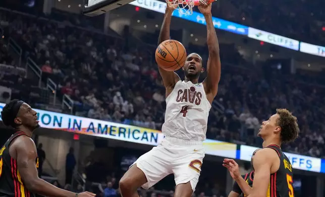 Cleveland Cavaliers center Evan Mobley (4) dunks between Atlanta Hawks forward Onyeka Okongwu, left, and guard Dyson Daniels (5) in the first half of an NBA basketball game in Cleveland, Wednesday, April 8, 2026. (AP Photo/Sue Ogrocki)