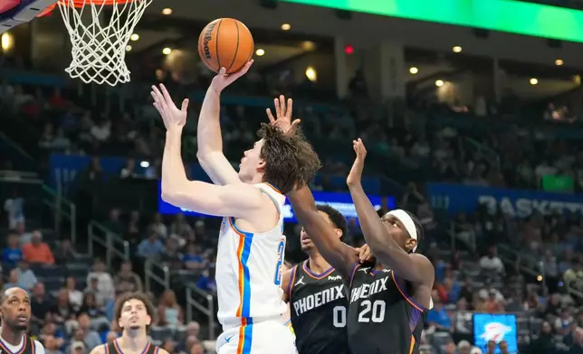 Oklahoma City Thunder forward Brooks Barnhizer, left, shoots in front of Phoenix Suns forwards Ryan Dunn, middle and Rasheer Fleming, right, during the second half of an NBA basketball game, Sunday, April 12, 2026, in Oklahoma City. (AP Photo/Kyle Phillips)