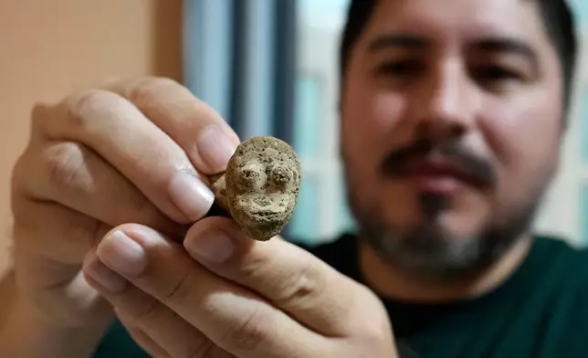 Archaeologist Manoel Fabiano da Silva Santos shows an anthropomorphic artifact found at the Quintela archaeological site at the National Department of Transport Infrastructure in Macapa, Amapa state, Brazil, Saturday, March 14, 2026. (AP Photo/Eraldo Peres)