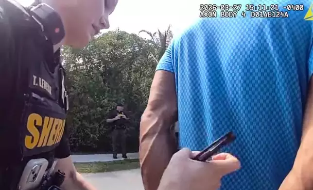 In this image taken from police body camera video released by the Martin County, Fla., Sheriff's Office, golfer Tiger Woods is taken into custody by sheriff's deputies following a car crash in Jupiter Island, Fla., Friday, March 27, 2026. (Martin County Sheriff's Office via AP)