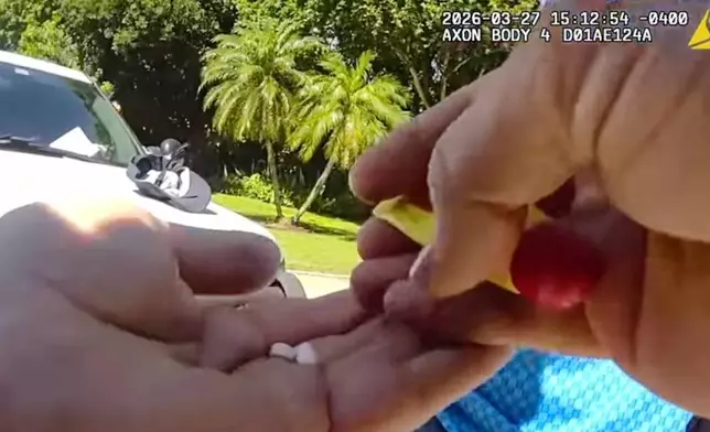 In this image taken from police body camera video released by the Martin County, Fla., Sheriff's Office, sheriff's deputies holds two pills from a search of golfer Tiger Woods' pants following a car crash in Jupiter Island, Fla., Friday, March 27, 2026. (Martin County Sheriff's Department via AP)