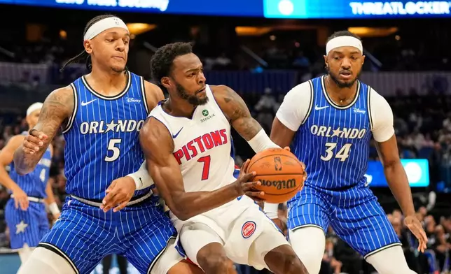 Detroit Pistons forward Paul Reed (7) looks to pass the ball as he gets caught between Orlando Magic forward Paolo Banchero (5) and center Wendell Carter Jr. (34) during the first half of an NBA basketball game, Monday, April 6, 2026, in Orlando, Fla. (AP Photo/John Raoux)