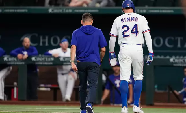 Texas Rangers' Brandon Nimmo (24) walks off the field with head athletic trainer Matt Lucero after suffering an unknon injury in the fifth inning of a baseball game against the Texas Rangers Wednesday, April 29, 2026, in Arlington, Texas. (AP Photo/Tony Gutierrez)