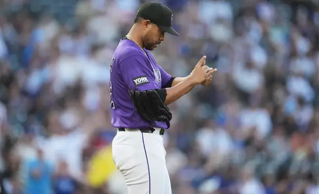 Colorado Rockies starting pitcher Jose Quintana rubs a new baseball after giving up a solo home run to Los Angeles Dodgers' Max Muncy in the second inning of a game Monday, April 20, 2026, in Denver. (AP Photo/David Zalubowski)