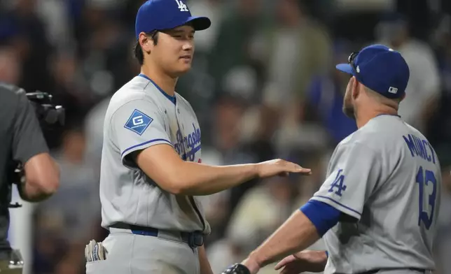 Los Angeles Dodgers' Shohei Ohtani, left, congratulates third baseman Max Muncy, right, after defeating the Colorado Rockies in a baseball game Monday, April 20, 2026, in Denver. (AP Photo/David Zalubowski)
