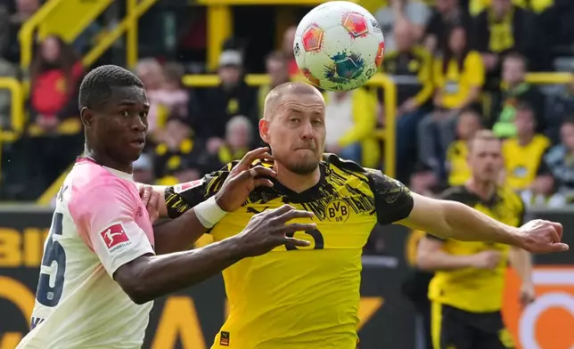 Leverkusen's Christian Kofane, left, challenges for the ball with Dortmund's Waldemar Anton, right, during the German Bundesliga soccer match between Borussia Dortmund and Bayer Leverkusen in Dortmund, Germany, Saturday, April 11, 2026. (AP Photo/Martin Meissner)