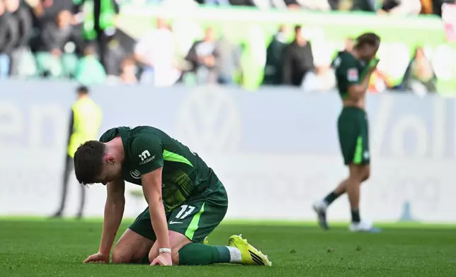 Wolfsburg's Dzenan Pejcinovic kneels on the pitch after losing the Bundesliga soccer match between Wolfsburg and Frankfurt, in Wolfsburg, Germany, Saturday April 11, 2026. (Swen Pförtner/dpa via AP)