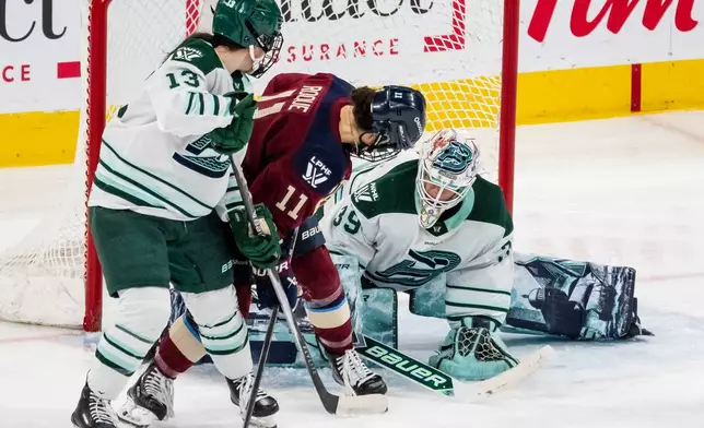 Boston Fleet goaltender Abbey Levy (39) makes a save against Montreal Victoire's Abby Roque (11) while Fleet's Liz Schepers (13) stands in front of the net during third-period PWHL hockey game action in Laval, Quebec, Friday, April 17, 2026. (Christopher Katsarov/The Canadian Press via AP)