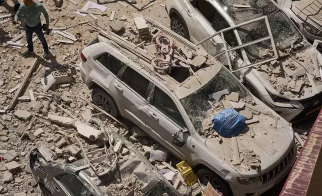 A man inspects the damage to cars and an apartment building struck by an Iranian missile in Ramat Gan, Israel, Monday, April 6, 2026. (AP Photo/Oded Balilty)