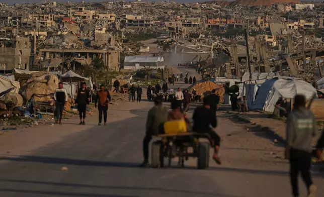Palestinians walk along a street surrounded by buildings destroyed during Israeli air and ground operations in Khan Younis, southern Gaza Strip, Thursday, April 9, 2026. (AP Photo/Abdel Kareem Hana)