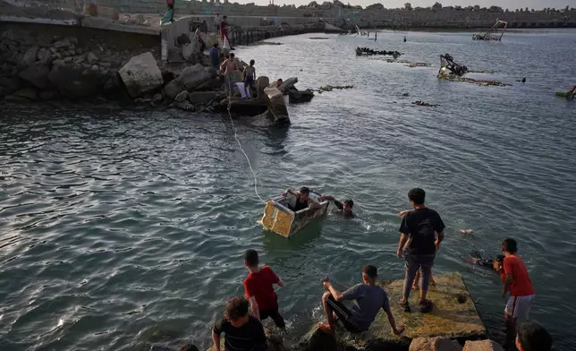Palestinian youth play while swimming in a port basin in Gaza City, Sunday, April 19, 2026. (AP Photo/Jehad Alshrafi)