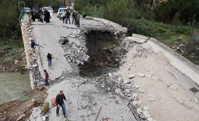 Displaced people cross a destroyed bridge as they return to their villages, following a ceasefire between Hezbollah and Israel, in Tayr Felsay village, southern Lebanon, Sunday, April 19, 2026. (AP Photo/Bilal Hussein)