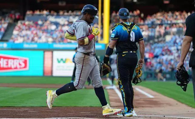 Atlanta Braves' Ronald Acuña Jr. scores past Philadelphia Phillies catcher J.T. Realmuto off of a hit by teammate Ozzie Albies during the first inning of a baseball game, Friday, April 17, 2026, in Philadelphia. (AP Photo/Matt Rourke)