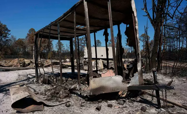 A burned trailer sits near a destroyed home as the Brantley Highway 82 fire burns, Thursday, April 23, 2026, near Nahunta, Ga. (AP Photo/Mike Stewart)