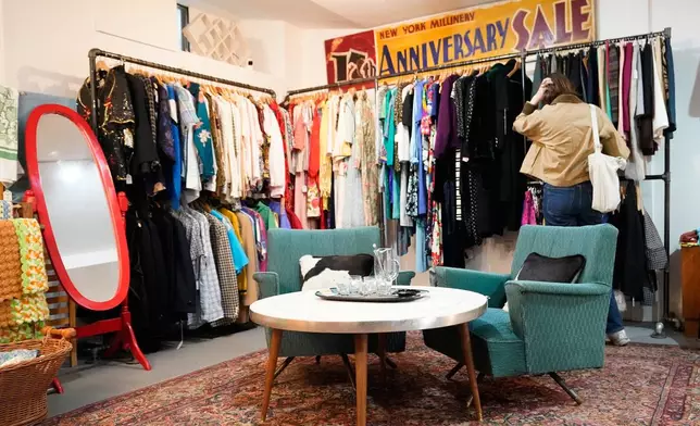 A shopper looks at a rack at Mothership, a vintage and thrift store, Thursday, March 26, 2026, in New York. (AP Photo/Alyssa Goodman)