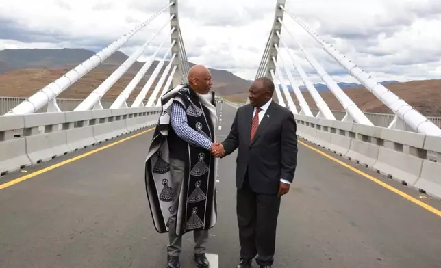 In this photo provided by the South African Government Communications and Information Services (GCIS), King of Lesotho Letsie III, left, shakes hand with South African President Cyril Ramaphosa following the official opening of the Senqu Bridge in Mokhotlong, Lesotho, Wednesday, April 22, 2026. (Elmond Jiyane/South African Government Communication and Information Services via AP)
