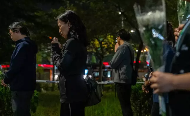 FILE - People offer flowers and pray for the victims near the site of Wednesday's fire at Wang Fuk Court, a residential estate in the Tai Po district of Hong Kong's New Territories, Sunday, Nov. 30, 2025. (AP Photo/Chan Long Hei, File)