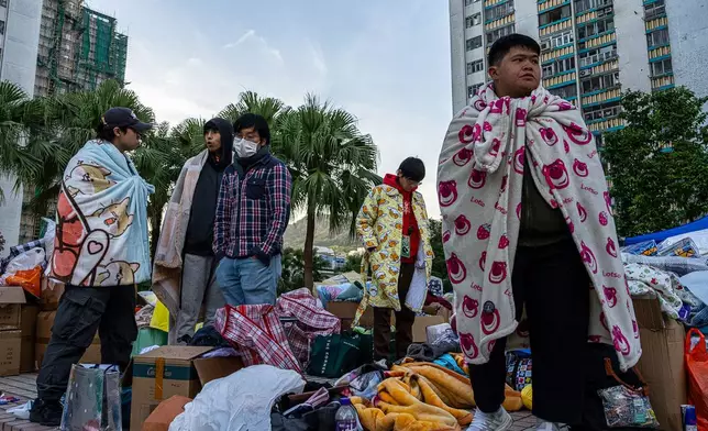 FILE - People stand amid donated supplies following the fire that started Wednesday at Wang Fuk Court, a residential estate in the Tai Po district of Hong Kong's New Territories, Friday, Nov. 28 2025. (AP Photo/Chan Long Hei, File)