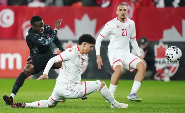 Canada's Tani Oluwaseyi, left, shoots as Tunisia's Alaa Ghram (18) and Moutaz Neffati (21) defend during the first half of an international friendly soccer match in Toronto, on Tuesday, March 31, 2026. (Chris Young/The Canadian Press via AP)