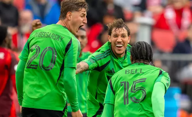 Austin FC's defender Jon Bell (15) is congratulated by teammates Nicolas Dubersarsky (20) and Guilherme Biro (29) after scoring on Toronto FC during the first half of an MLS soccer game in Toronto, Saturday, April 18, 2026. (Frank Gunn/The Canadian Press via AP)