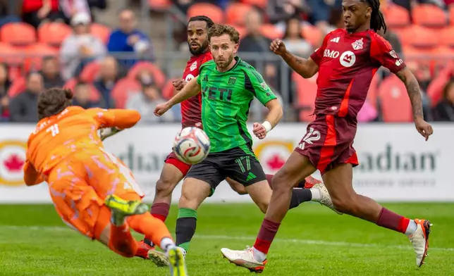 Toronto FC's goalkeeper Luka Gavran (1) dives to make a save on Austin FC's Jon Gallagher (17) as Toronto FC's Zane Monlouis (12) joins the fray during the first half of an MLS soccer game in Toronto, Saturday, April 18, 2026. (Frank Gunn/The Canadian Press via AP)