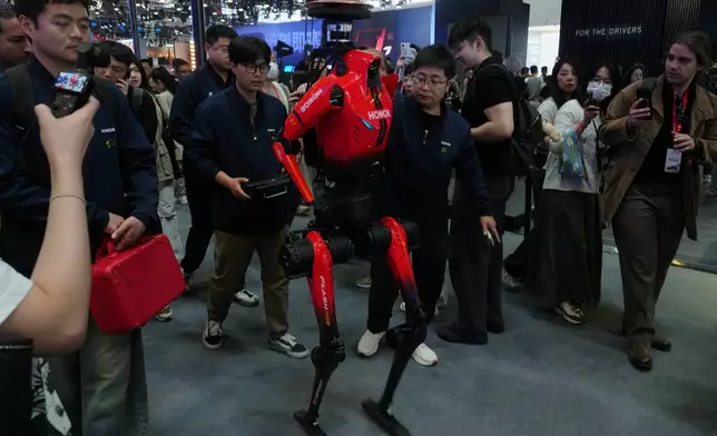 Honor, the humanoid robot which has won the humanoid robot half-marathon last weekend is surrounded by visitors as it visiting the Auto China 2026, in Beijing, Friday, April 24, 2026. (AP Photo/Andy Wong)